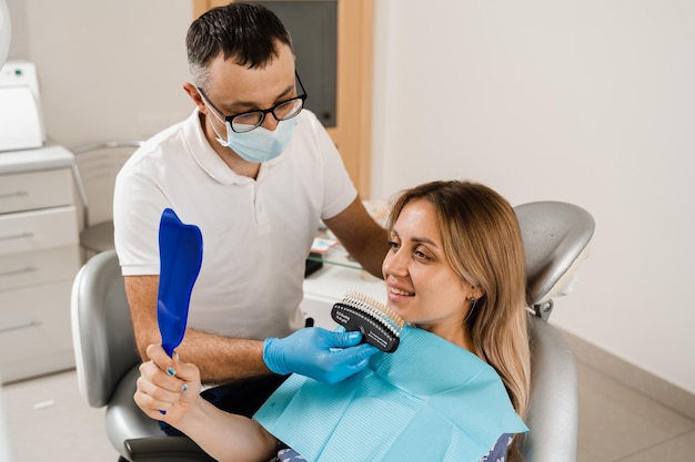 Sbiancamento dei denti Paziente che guarda la guida alle sfumature di colore dei denti Odontoiatria Medico che controlla i campioni di corrispondenza del colore dei denti nella clinica dentale