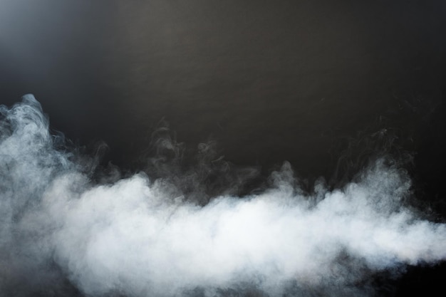 Sbuffi densi e soffici di fumo bianco e nebbia su sfondo nero, nuvole di fumo astratte, movimento sfocato fuori fuoco. Il fumo soffia dal ghiaccio secco della macchina vola e svolazza nell'aria, effetto texture