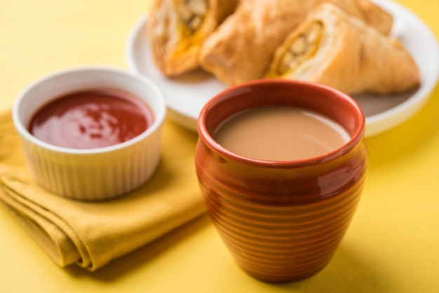 Sbuffo di verdure ripieno o samosa, famoso snack indiano da forno, servito con ketchup e tè caldo, messa a fuoco selettiva