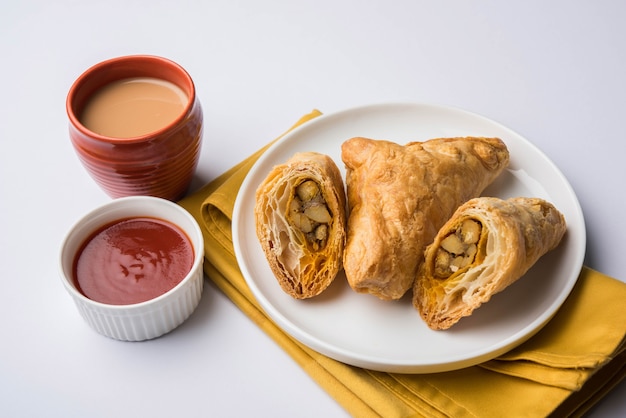 Sbuffo di verdure ripieno o samosa, famoso snack indiano da forno, servito con ketchup e tè caldo, messa a fuoco selettiva