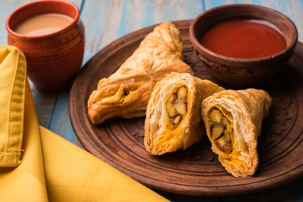 Sbuffo di verdure ripieno o samosa, famoso snack indiano da forno, servito con ketchup e tè caldo, messa a fuoco selettiva