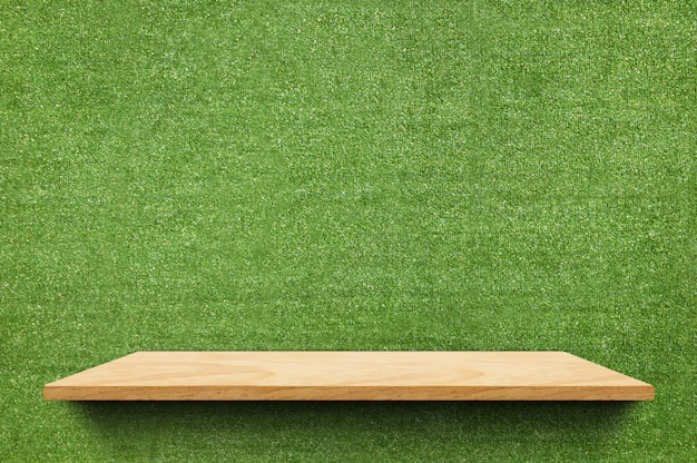 Scaffale di legno vuoto del bordo al fondo falso della parete dell'erba verde