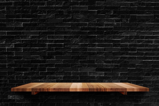 Scaffale di legno vuoto del bordo al fondo nero del muro di mattoni