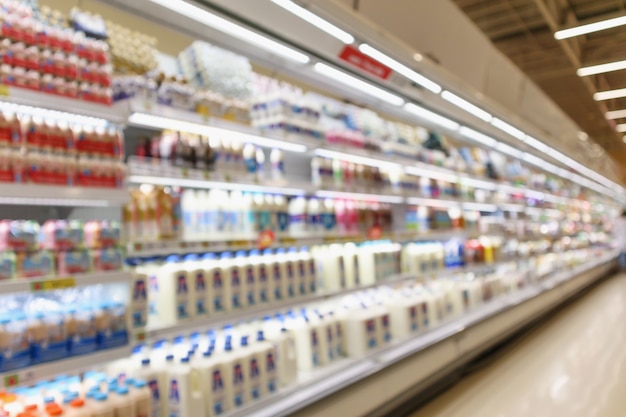 Scaffali del frigorifero della drogheria del supermercato della sfuocatura astratta con le bottiglie di latte fresco e i prodotti lattiero-caseari