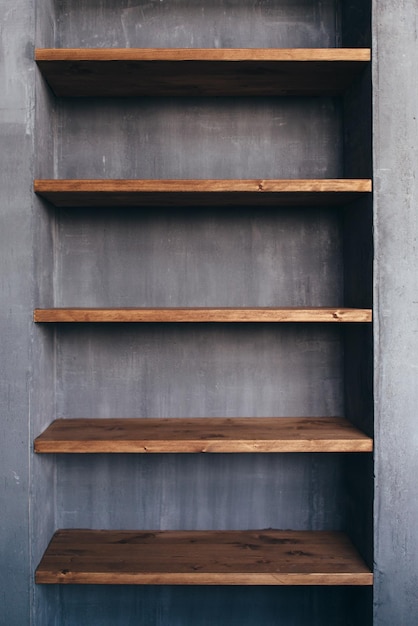 Scaffali di legno vuoti al muro di cemento nell'interiore domestico