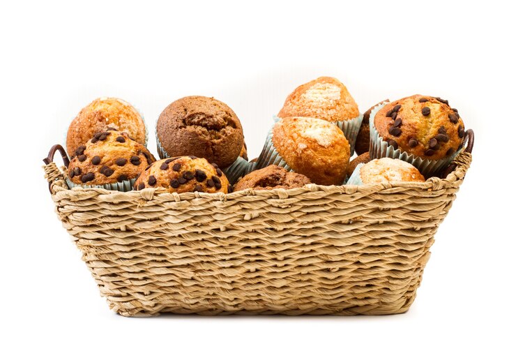 Scaglie di cioccolato e cupcakes alla vaniglia in un cesto di vimini su bianco