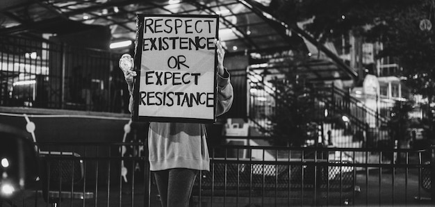 Scala di grigio di un cartello di protesta con testo modificabile tenuto da una giovane manifestante