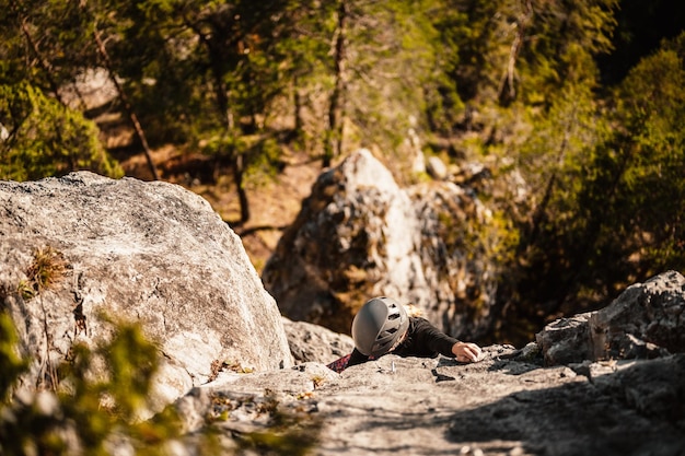 Scalatore che indossa l'attrezzatura da arrampicata Praticare l'arrampicata su una parete rocciosa Arrampicata sportiva e concetto di bouldering scalatore si arrampica su una parete rocciosa