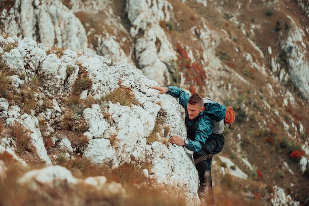 Scalatore che supera una difficile via di arrampicata sulla montagna rocciosa Avventura sport estremo all'aperto