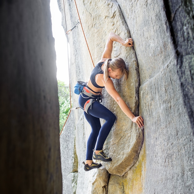 Scalatore femminile che si arrampica con la corda su una parete rocciosa