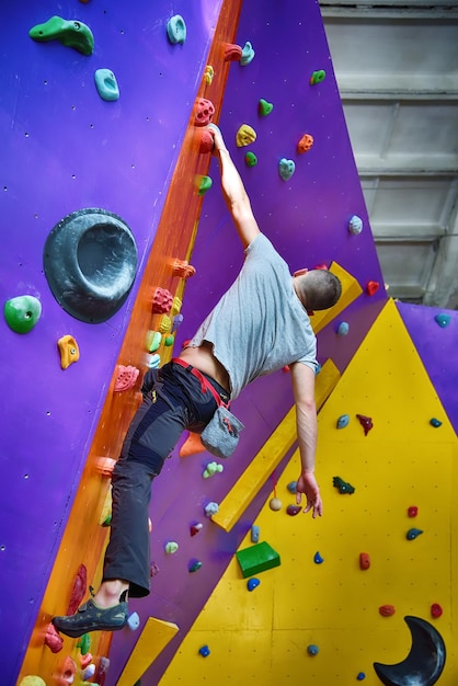 Scalatore su parete da arrampicata artificiale in palestra boulder senza assicurazione