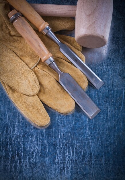 Scalpelli e guanti di sicurezza per magli di legno più solidi su una superficie metallica graffiata.