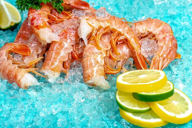 scampi di gamberi freschi rossi con e senza testa, giacciono sullo sfondo del mare blu ghiaccio, ciliegia