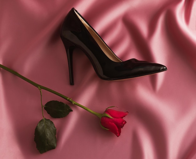 Scarpa con tacco alto e fiore rosa su seta rosa San Valentino o 8 marzo Concetto di moda Vista dall'alto