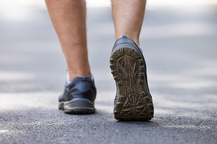 Foto scarpe da fitness e camminata con un uomo su una strada durante un allenamento cardio o di resistenza all'aperto esercizio per la schiena e salute con un corridore maschio o atleta che si allena su una strada per il benessere o lo stile di vita