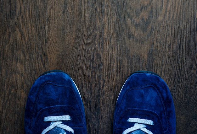 Scarpe da ginnastica blu sul pavimento di legno