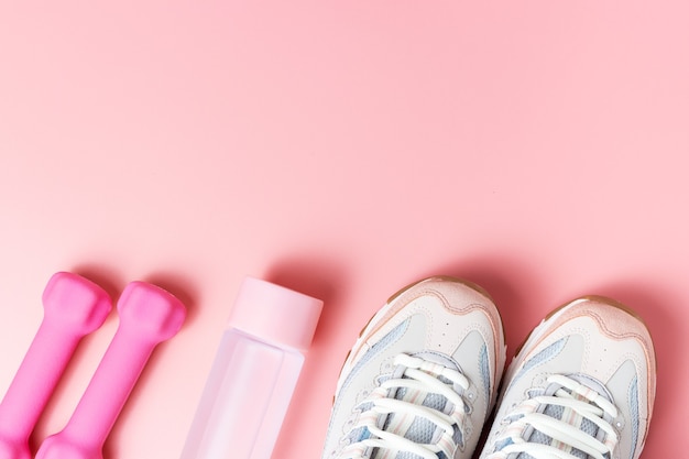 Scarpe da ginnastica, manubri su una vista dall'alto di sfondo rosa