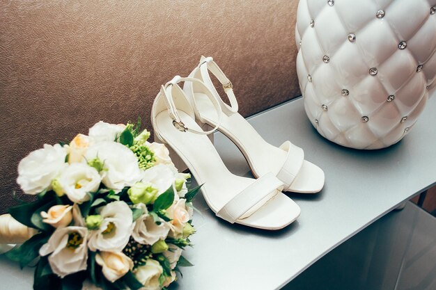 Scarpe da sposa bianche da donna su uno scaffale con un concetto di bouquet per l'agenzia di eventi