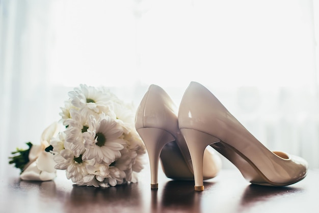 Scarpe da sposa e bouquet contro la finestra