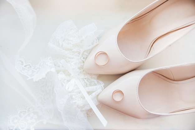 Scarpe da sposa, giarrettiera e fedi nuziali della bella sposa