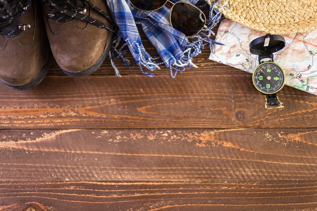 Scarpe da trekking con mappa topografica e bussola su uno sfondo di legno.