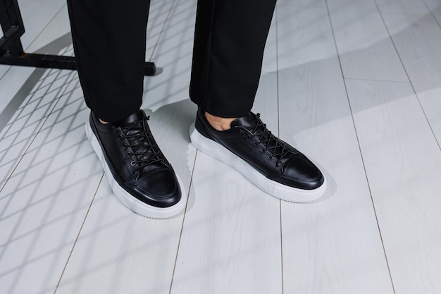 Scarpe da uomo moderne Gambe maschili in pantaloni neri e scarpe da ginnastica casual nere Scarpe alla moda da uomo