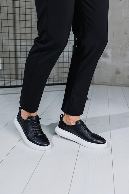 Scarpe da uomo moderne Gambe maschili in pantaloni neri e scarpe da ginnastica casual nere Scarpe alla moda da uomo