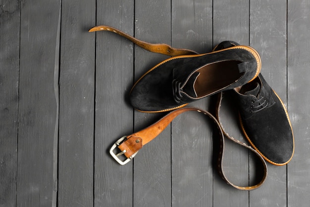 Scarpe e accessori per uomo giacciono sul pavimento di legno