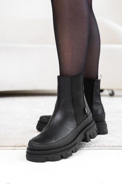 Scarpe eleganti nere del primo piano sulle gambe delle donne. Stivali invernali in pelle, foto di concetto di calzature da donna alla moda