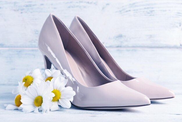 Scarpe femminili con fiori su sfondo di legno