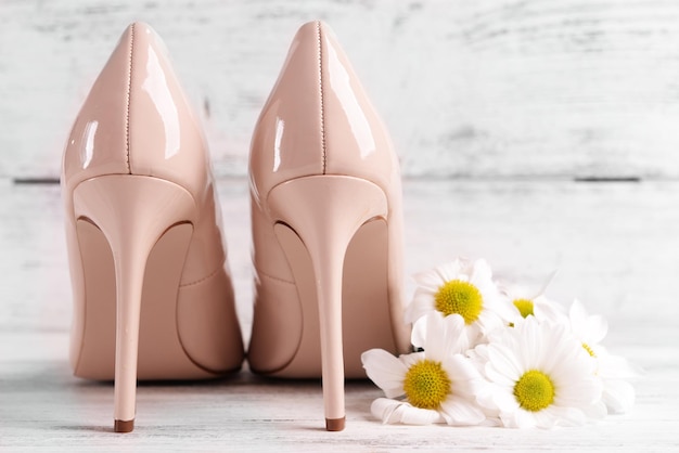 Scarpe femminili con fiori su sfondo di legno