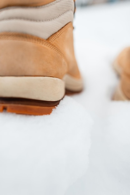 Scarpe invernali in pelle sulla neve, primo piano. l'uomo con gli stivali beige cammina in una giornata invernale.