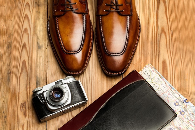 Scarpe marroni una macchina fotografica e una mappa su un tavolo di legno