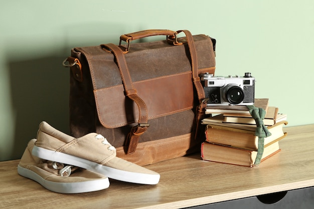 Scarpe maschili con valigetta, libri e macchina fotografica su tavola di legno