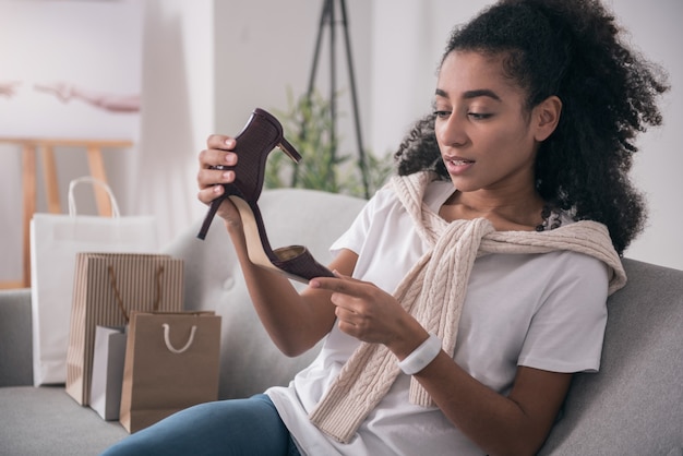 Scarpe perfette. Bella giovane donna che tiene le scarpe mentre le guarda