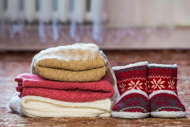 Scarpe rosse con stivali di Capodanno e una pila di maglioni lavorati a maglia