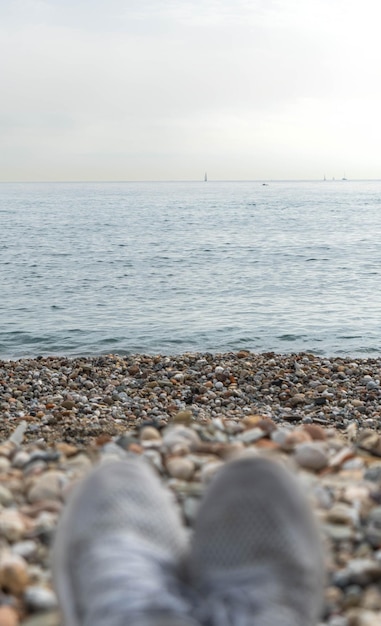 Scarpe sfocate sullo sfondo di ghiaia con il mare in lontananza