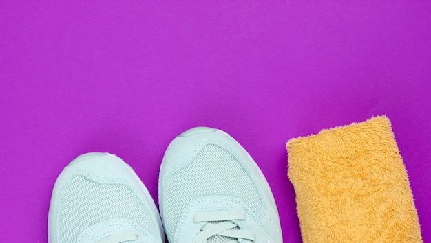 Scarpe sportive, asciugamano su uno sfondo viola