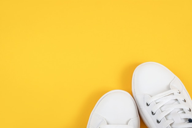 Scarpe sportive bianche, scarpe da ginnastica con lacci su sfondo giallo. Concetto di stile di vita sportivo Vista dall'alto Posa piatta