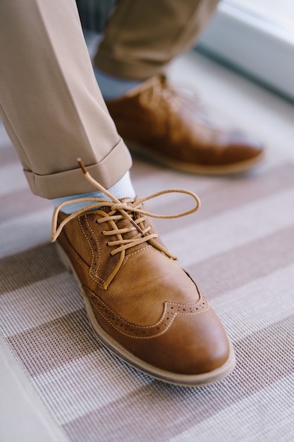 Scarpe stringate marroni allacciate sul primo piano delle gambe degli sposi
