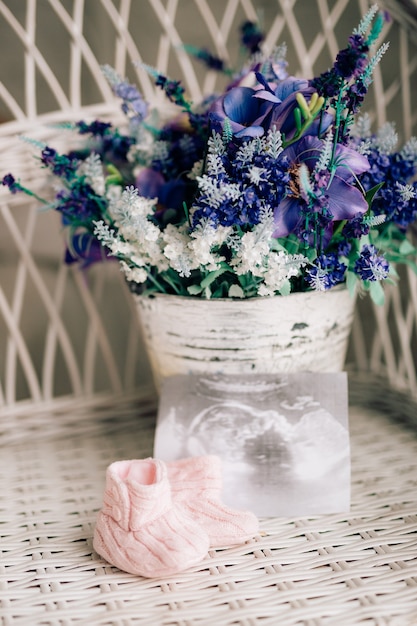 Scarpette per neonati su una sedia di vimini e un bouquet di lavanda su un ba