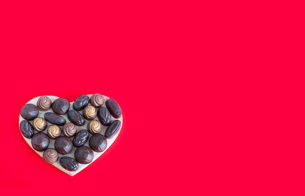 Scatola a forma di cuore di San Valentino con cioccolatini su un rosso