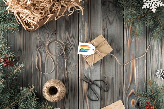 Scatola avvolta artigianale in tessuto organico naturale con etichetta arcobaleno biglietto festivo con forbici corda sleave sul tavolo di legno