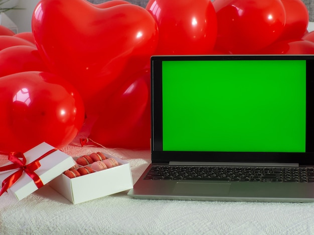 Scatola con biscotti macaron e laptop con schermo chroma key sul letto