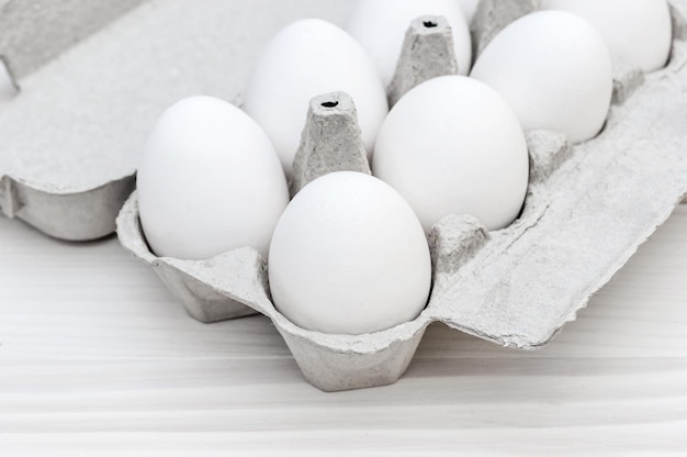 Scatola con le uova sul tavolo di legno bianco