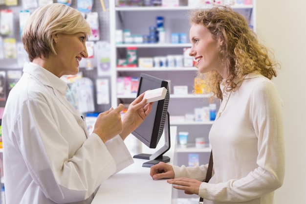 Scatola della medicina della tenuta del farmacista che parla con cliente