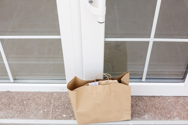 Scatola di cartone per pacchi nella porta d'ingresso. Consegna porta a porta di merce buona durante la quarantena, consegna fuori porta, acquisto di e-commerce durante il blocco del covid-19, concetto di distanza sociale.