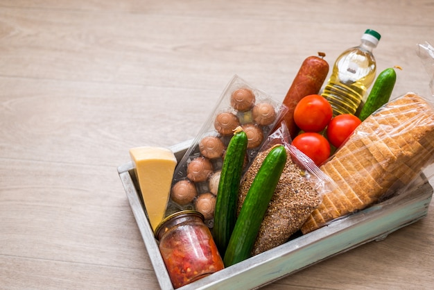 Scatola di donazione con cibo. Assistenza umanitaria durante la pandemia di coronavirus. Scatola con ingredienti essenziali, pasta, cereali e verdure.