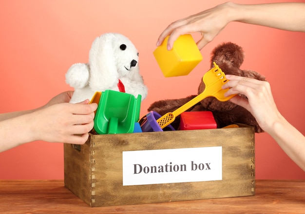 Scatola di donazione con giocattoli per bambini su sfondo rosso primo piano
