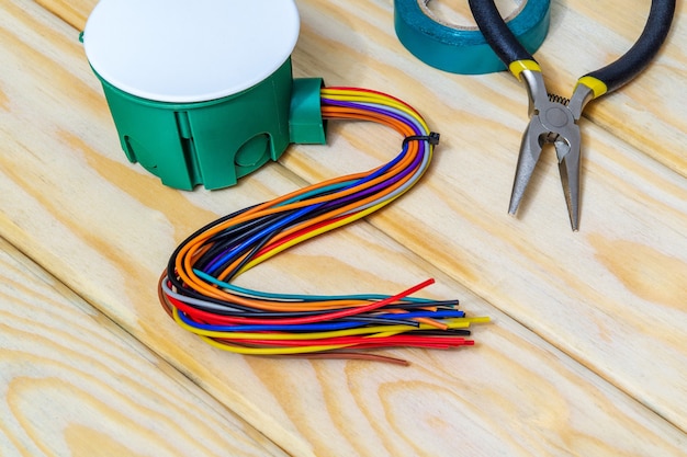 Scatola di giunzione elettrica con fili e strumento su tavole di legno nere solitamente utilizzate nel processo di installazione elettrica